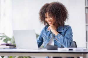 Mulher sorridente lendo notícia no computador sobre evento de tecnologia ligado ao G20.