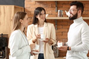 Três profissionais sorrindo e conversando enquanto tomam café no Brainstorm Coffee.