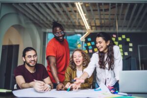 Empreendedorismo sustentável: grupo de empreendedores em coworking discutindo o projeto alegremente.