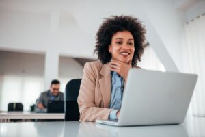 Móveis para escritório: mulher sorridente trabalhando em coworking.
