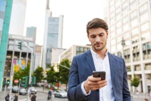 ecossistema de inovação​: homem na rua em meio a prédios mexendo no celular
